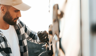 Junger Mann befestigt LKW-Plane an Lkw
