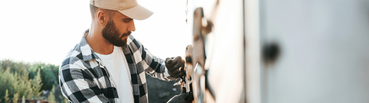 Grundqualifikation Lkw und Bus Ladungssicherung Junger Mann befestigt LKW-Plane an Lkw