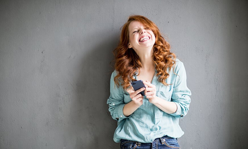 Frau mit Handy in der Hand freut sich