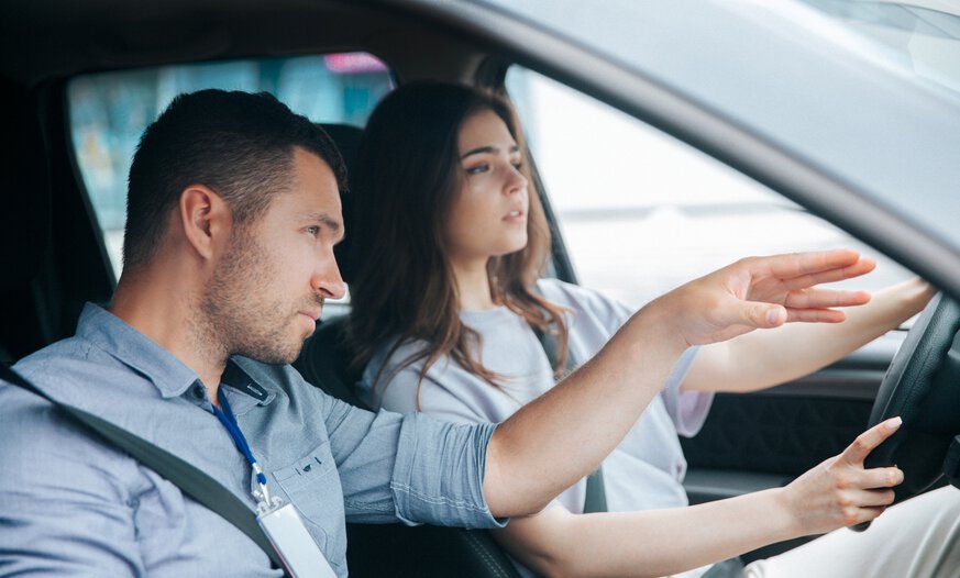 Fahrlehrer zeigt Schüler mit der Hand den Weg