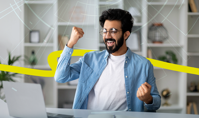 Jubelnder Mann vor Laptop in modernem Büro