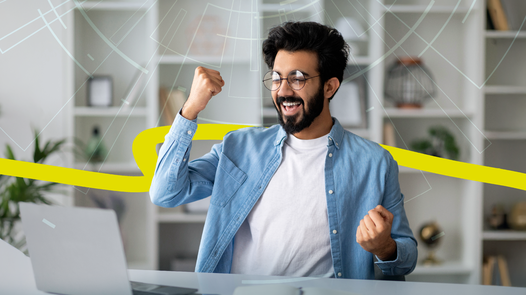 Jubelnder Mann vor Laptop in modernem Büro