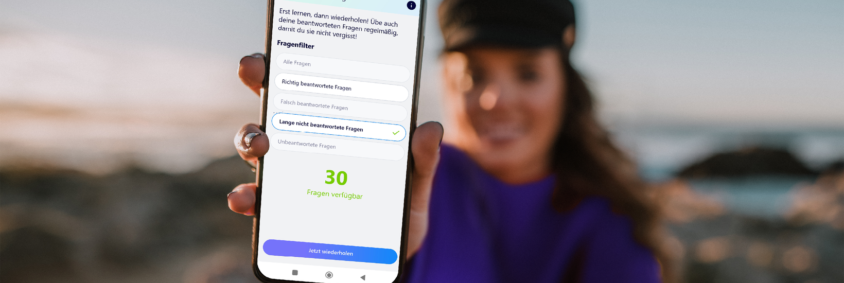 Junge Frau im Hintergrund hält Smartphone mit Führerschein Lern App nach vorne