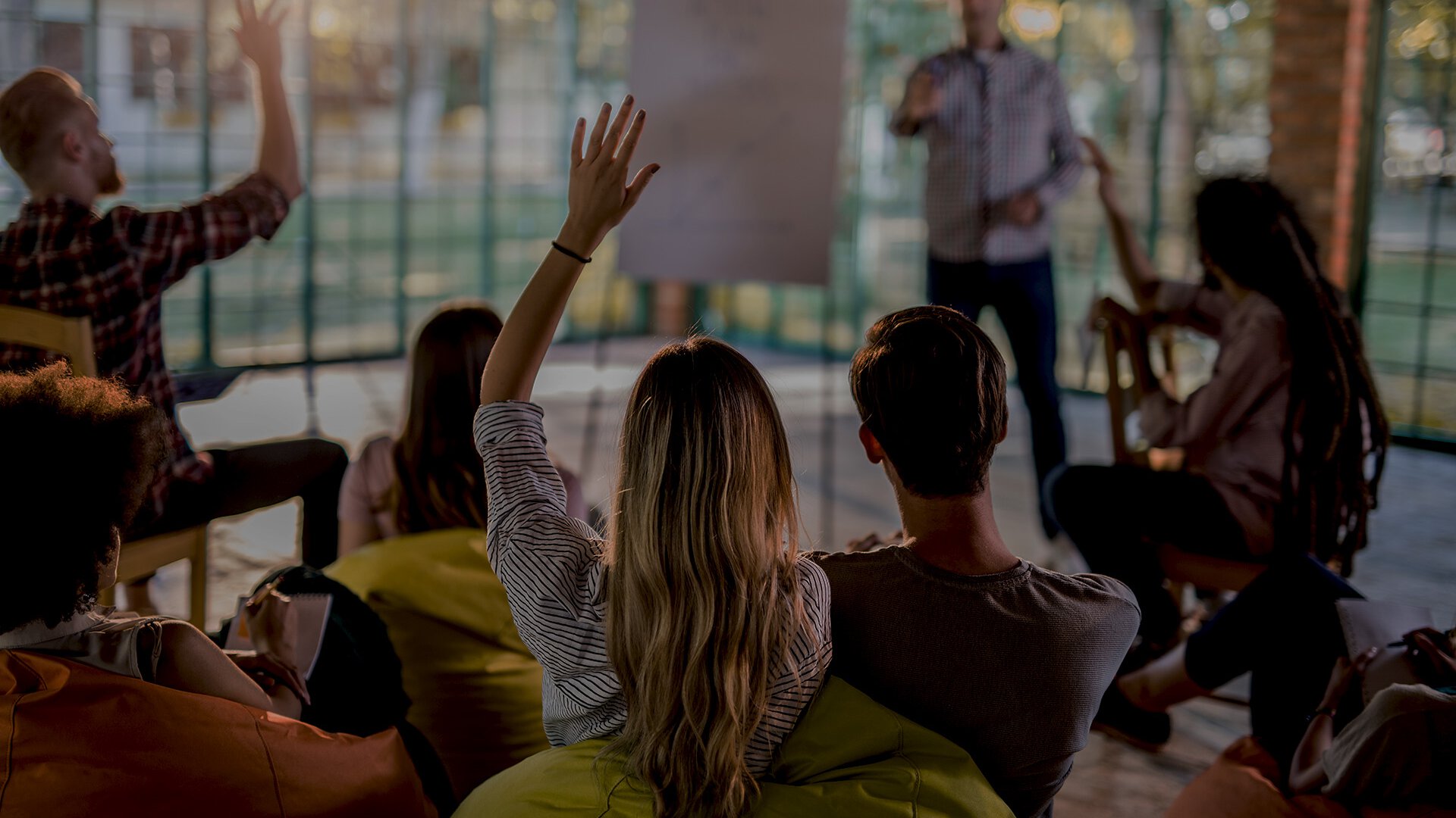 Mehrere Personen sitzen auf Stühlen vor einer Person die an einem Flipchart präsentiert